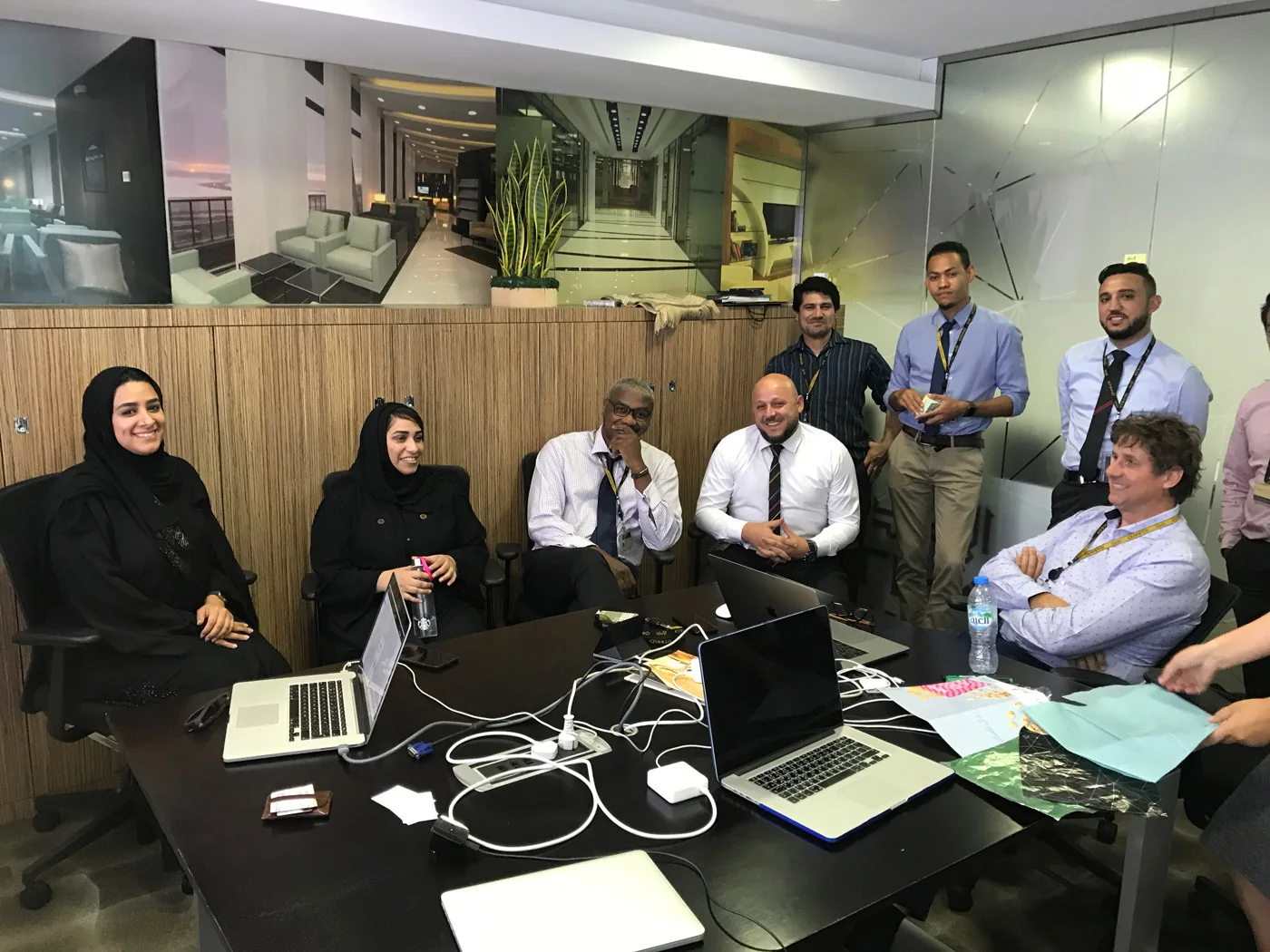 Een UX-overleg met het managementteam van Etihad Airways, rond een tafel met laptops en notities.