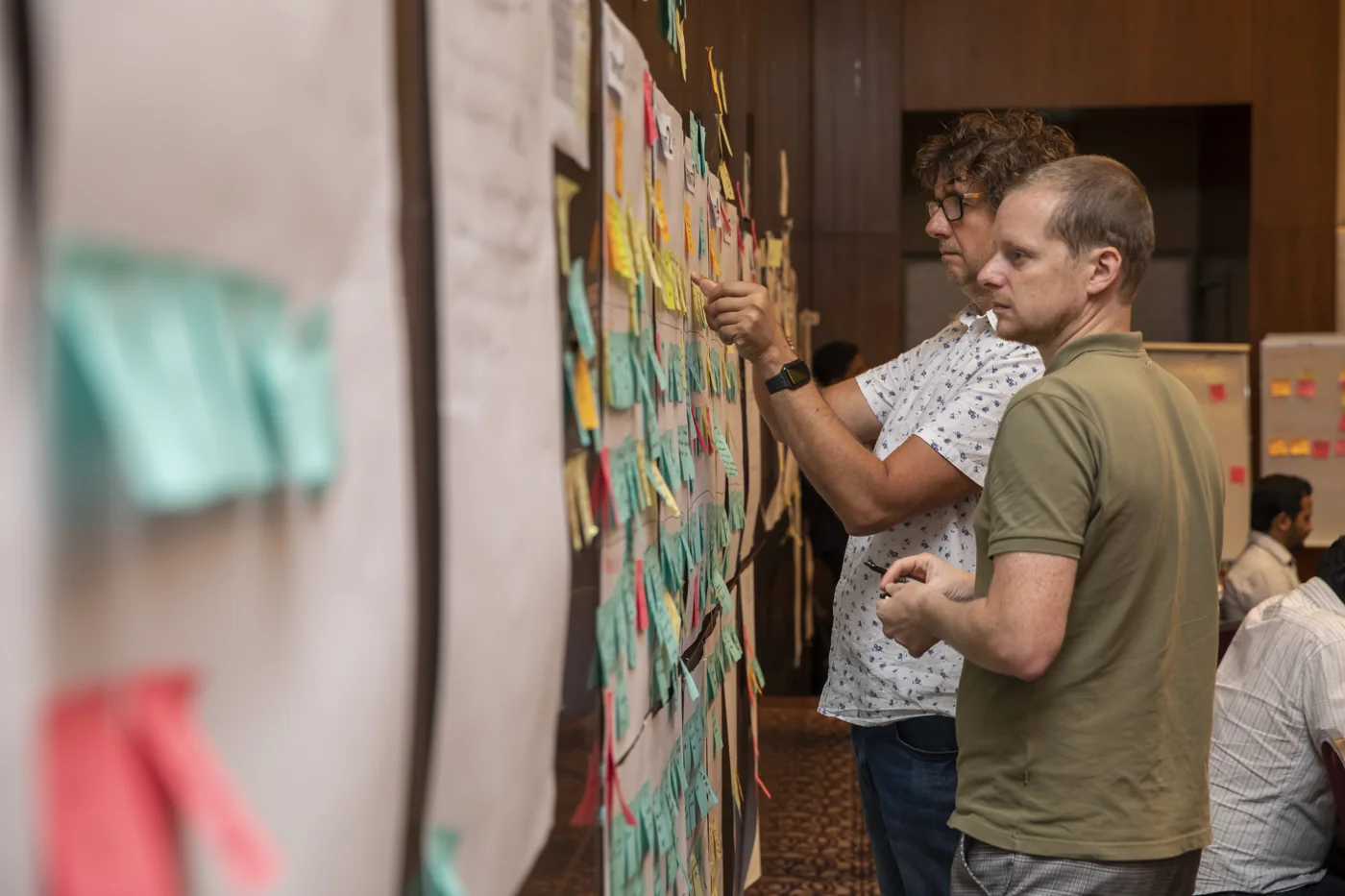 Makers van Epicstories werken samen aan een wand vol gekleurde ideeënbriefjes.